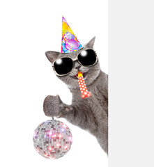Poster - Happy cat wearing party cap and sunglasses looks from behind empty banner and shows dico ball and  blows into party horn. isolated on white background