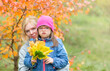 © Ermolaev Alexandr - Mother hugs hr little daughter with Downs syndrom at autumn park. Empty space for text