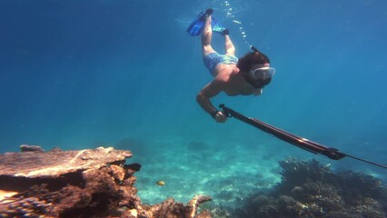 Canvas Print - Scuba diving, woman or swimming underwater by coral reef for adventure or wildlife in ocean with spear. Diver, person or snorkeling by seabed with freedom for travel, vacation or undersea exploration