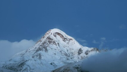 Wall Mural - Stepantsminda, Gergeti, Georgia. Mount Kazbek Covered Snow In Winter Sunrise. Morning Dawn Colored Top Of Mountain In Pink Colors. Awesome Winter Georgian Nature Landscape. Time Lapse Timelapse 4K.