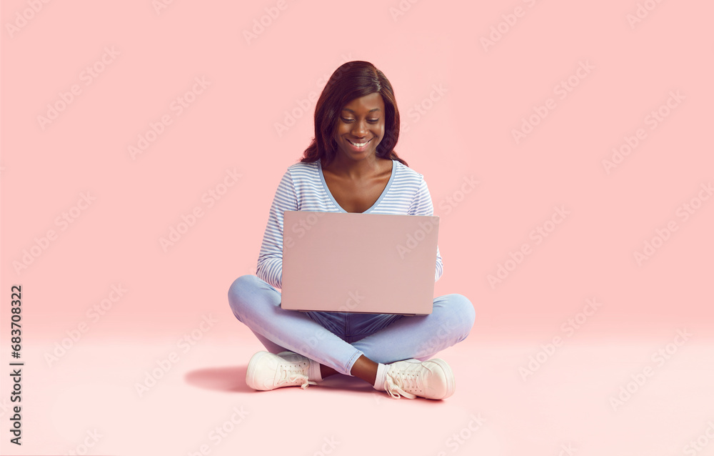 Happy woman working on laptop. Young African American girl in light ...