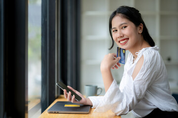 Woman plans to use credit card for online shopping on phone. Digital banking and online payment.