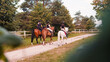 Horsewomen riding beautiful horses along the trail at the equestrian center on a bright summer day. Horse gait walks concept.