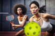 Asian and african american women playing a competitive doubles game of pickleball