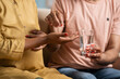 © WESTOCK - Close up shot of husband giving pills or medicines to pregnant wife at home - concept of Pregnancy care, Maternal health and Prenatal bonding.