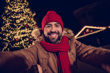 Canvas Print - Photo of dreamy cheerful young guy dressed coat recording video x-mas vlog outdoors urban fair park