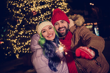 Poster - Portrait of lovely peaceful partners arm hold bengal lights stick magic christmastime fairy capital center tree garland outside