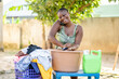 portrait of beautiful african lady washing and communicating on smartphone- manual cloth washing outdoor