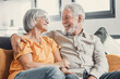 © Daniel - Happy laughing older married couple talking, laughing, standing in home interior together, hugging with love, enjoying close relationships, trust, support, care, feeling joy, tenderness.
