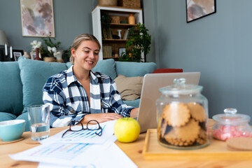 Young freelance businesswoman, financial advisor, web developer, marketing expert having video call on laptop computer, working from home online while sitting on the floor of her apartment