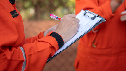 Wall Mural - Action of safety officer is writing and check on checklist document during safety audit and inspection at drilling site operation. Industrial expertise occupation working scene.