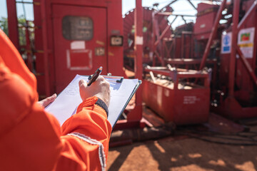 Maintenance engineer performs audit and inspection the power generator machine (as background) at the oil refinery plant working site. Industrial safety working wit people action, selective focus.