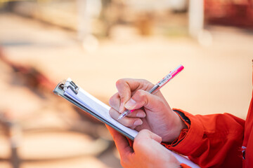 Wall Mural - Action of safety officer is writing and check on checklist document during safety audit and inspection at drilling site operation. Industrial expertise occupation working scene.