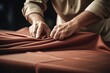 A person is seen cutting a piece of cloth on a table. This image can be used for sewing, tailoring, or crafting projects