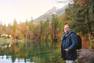 outdoor portrait of handsome mature man enjoying nice day outside, visiting small mountain lake, fal
