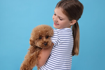 Canvas Print - Little child with cute puppy on light blue background. Lovely pet