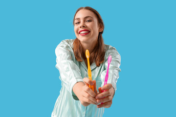 Sticker - Beautiful young woman with toothbrushes on blue background