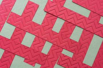 Wall Mural - overlapping red paper stripes with embossed chevron or zig zag pattern on rough green paper