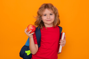 Aufkleber - Back to school. School boy with book and apple. School child student learning. Elementary school child. Portrait of funny pupil learning on yellow isolated background.