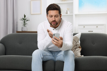 Wall Mural - Man blowing kiss during video chat via smartphone at home. Long-distance relationship