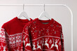 Rack with Christmas sweaters on light background