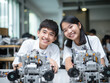 © Kedek Creative - male and female robotic asian students, smile while assembling their work in a hands-on laboratory