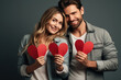 © Atchariya63 - Happy young couple smileing and holding red hearts isolated on gray background