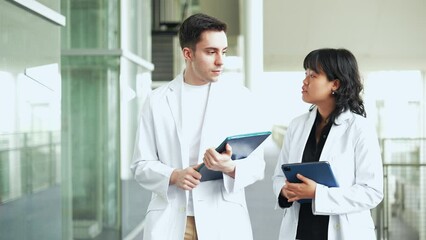 Poster - Multinational group walking in the lobby wearing white coats.