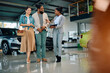 © Drazen - Happy black saleswoman talks to couple who is looking for new car in showroom.