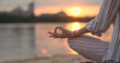 © Oleksii - Woman practicing yoga, joins her index finger and thumb to sign apana mudra. Sunset, river, beach, orange sun reflected on surface water.