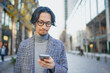 © HML - 街中でスマートフォンを使うジャケットを着た男性