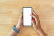 Female hands holding smartphone with mockup of blank screen on desk in office room.