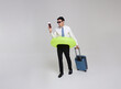 Funny worker ready to go on summer holiday. Happy smiling asian business man holding inflatable swim ring and passport ticket walking with suitcase isolated on white background.
