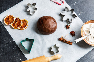 Wall Mural - baking, cooking and christmas concept - close up of gingerbread dough, molds, spices and flour with rolling pin on black table top