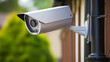 Une caméra de surveillance qui est fixée sur le mur d'une maison à l'extérieur. 