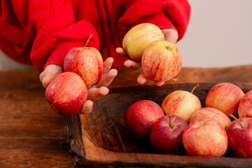 Poster - Nutrient-rich display: A woman's hands arrange fresh red apples on a wooden backdrop, embodying the principles of healthy eating, vegetarianism, and the nutritional goodness of fruits