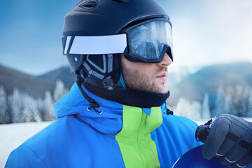 Wall Mural - Close up of the ski goggles of a man with the reflection of snowed mountains. A mountain range reflected in the ski mask. Portrait of man at the ski resort on the background of mountains and sky