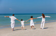 © Darren Baker - Mother, Father and Children Family Walking on Beach in White Clothes