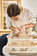 © JoseIMartin - Artisan woman shaping clay on pottery wheel while working in her workshop. Hobby and handicraft concept.