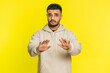 Hey you, be careful. Strict Indian man warning with admonishing hands gesture, saying no, be careful, scolding and giving advice to avoid danger, disapproval sign. Guy on yellow studio background