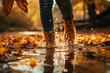 In the autumn rain, the feet of a young woman walking in a puddle with beautiful autumn leaves fell into the water. Autumn mood. macro