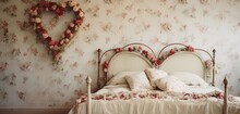 A Vintage-inspired Bedroom With Floral Wallpaper, An Antique Bedspread, And A Heart-shaped Wreath Of Dried Rose Petals On The Wall.