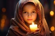 Portrait of a cute, lovely little girl with a headscarf holding a candle in a church