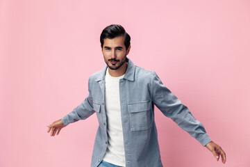 Poster - Fashion brunette man with beard happiness open mouth jumping and running with his arms spread on a pink background in a white T-shirt and jeans smile and joyful emotion on his face, copy space