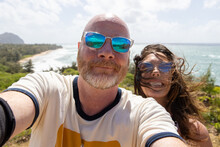 Happy Middle Aged Couple Together On Vacation At Ocean Beach. The Man And Woman Are Smiling For A Selfie Overlooking The Sea. 