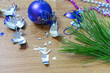 Broken Christmas tree decorations litter floor after holiday party fragments of blue New Year ball, a holiday decoration on a wooden laminate next to a green branch Sharp shards of broken glass toys