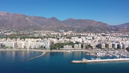 Wall Mural - Picturesque autumn view from drone of coastal Mediterranean city of Marbella on background of mountain range overlooking sea harbour on summer day, Andalusia, Spain