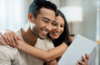 © HockleyMedia/peopleimages.com - Hug, happy and couple with tablet on sofa relax with social media, movies or streaming film at home. Love, smile and people in living room with digital, search or app for show, video or communication