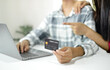 © Orathai - E-commerce Concept. Happy couple holding credit card enjoying doing online shopping and using laptop enter their card number in-app to purchase and payment in the internet store