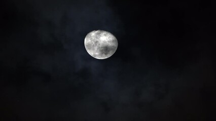 Wall Mural - Bright white moon craters and ridges rises in sky as clouds pass below at night